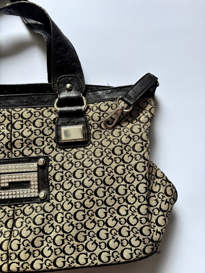 Guess Monogram Canvas Shoulder Bag (Category: Tote Bags) located in Manila. Submitted by anik.anik_ph (Listing ID 1462089959, Image 3). Description: - Classic Guess monogram tote bag - Color: Beige and black canvas with black leather trim - Iconic all-over G logo pattern - Front detail: Decorative G logo plate with rhinestones - Features: Double top handles - Style: Stylish everyday bag vintage GUESS monogram canvas tote handbag W 17 inches L 11 
