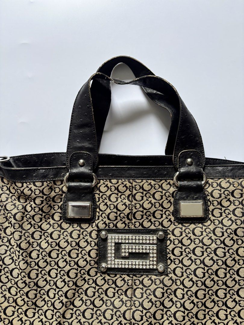 Guess Monogram Canvas Shoulder Bag (Category: Tote Bags) located in Manila. Submitted by anik.anik_ph (Listing ID 1462089959, Image 2). Description: - Classic Guess monogram tote bag - Color: Beige and black canvas with black leather trim - Iconic all-over G logo pattern - Front detail: Decorative G logo plate with rhinestones - Features: Double top handles - Style: Stylish everyday bag vintage GUESS monogram canvas tote handbag W 17 inches L 11 