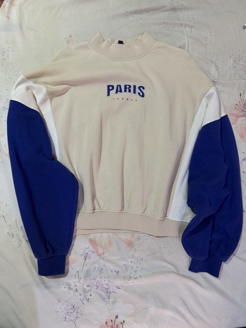 H&M Sweatshirt (Category: Coats, Jackets and Outerwear) located in Manila. Submitted by cesca28 (Listing ID 1462165326, Image 1). Description: Cream sweatshirt with blue and white sleeves. Features 'PARIS FRANCE' graphic on the front. Mock neck with ribbed cuffs and hem. Comfortable and stylish piece for your casual outfits..