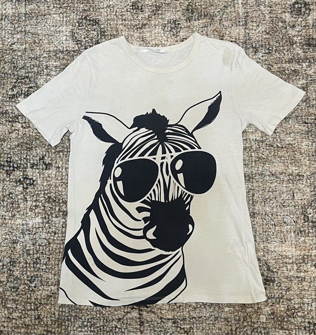 H&M Zebra Sunglasses Graphic T-Shirt (Category: Babies & Kids Fashion) located in Taguig. Submitted by ethans_mom (Listing ID 1462136102, Image 1). Description: - Cool graphic tee featuring a zebra in sunglasses - Light grey color - Short sleeves, crew neck - Estimated size: Small to Medium - Perfect for casual outfits - Note: Faint stain on the right shoulder area (please check photos for details).