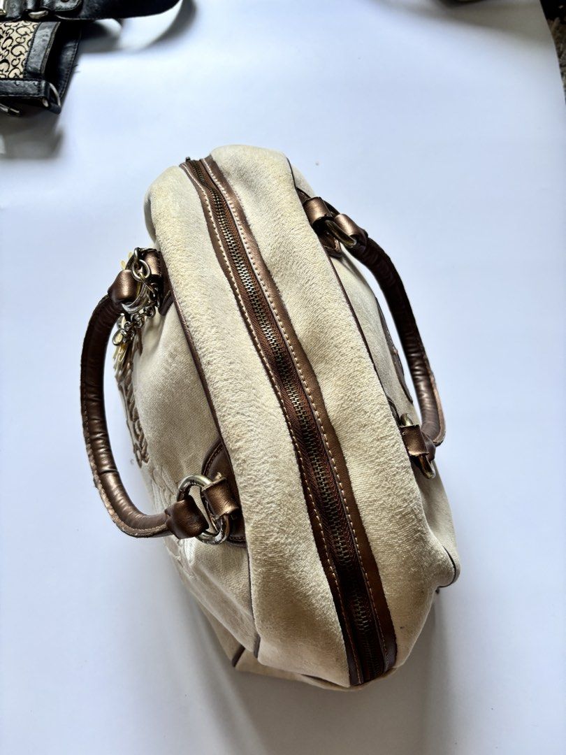 Juicy Couture Velour Handbag (Category: Luxury Bags & Wallets) located in Manila. Submitted by anik.anik_ph (Listing ID 1462178613, Image 3). Description: - Cream velour Juicy Couture handbag - Classic embroidered logo and rose detail - Signature pink crown and logo interior lining - Zipper closure - Metallic bronze handles - Cute charm attached to the side Juicy Couture velour Bag W 14 inches L 12 inches Grab ₱3000 light-colored velour or suede 