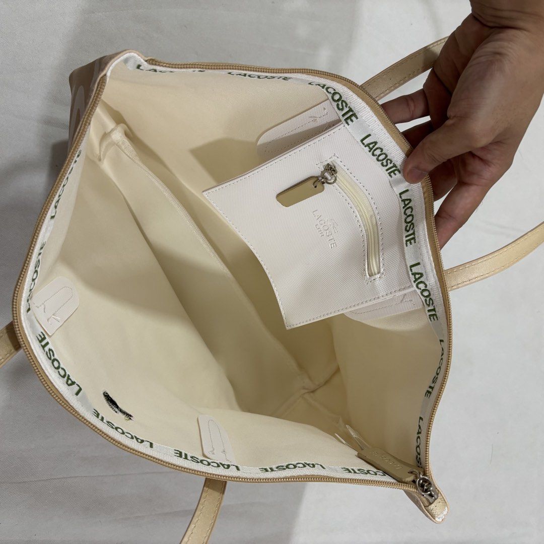 Lacoste Beige Tote Bag with Large Logo Print (Category: Tote Bags) located in Cavite. Submitted by itsayaaa (Listing ID 1462093261, Image 3). Description: - Beige Lacoste tote bag - All-over white logo print - Zippered closure - Two comfortable handles - Multiple interior compartments - Includes a small zippered pouch - Interior lining with repeated Lacoste logo - Ideal for everyday use.