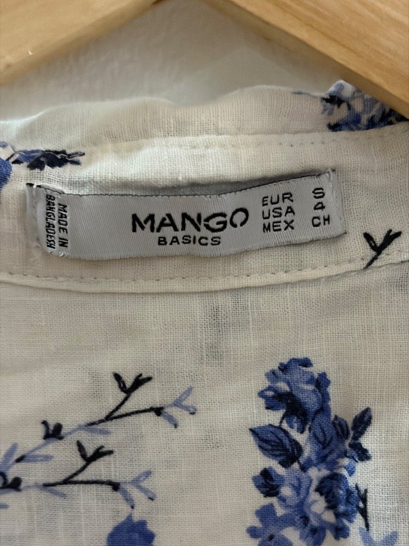 Mango Basics White Floral Button-Up Shirt (Category: Longsleeves) located in San Juan City. Submitted by sel.ler (Listing ID 1462126552, Image 2). Description: - Brand: Mango Basics - Color: White with blue floral print - Style: Button-up shirt - Sleeves: Long sleeves with button cuffs - Pockets: Single chest pocket - Material: Lightweight - Occasion: Casual wear.