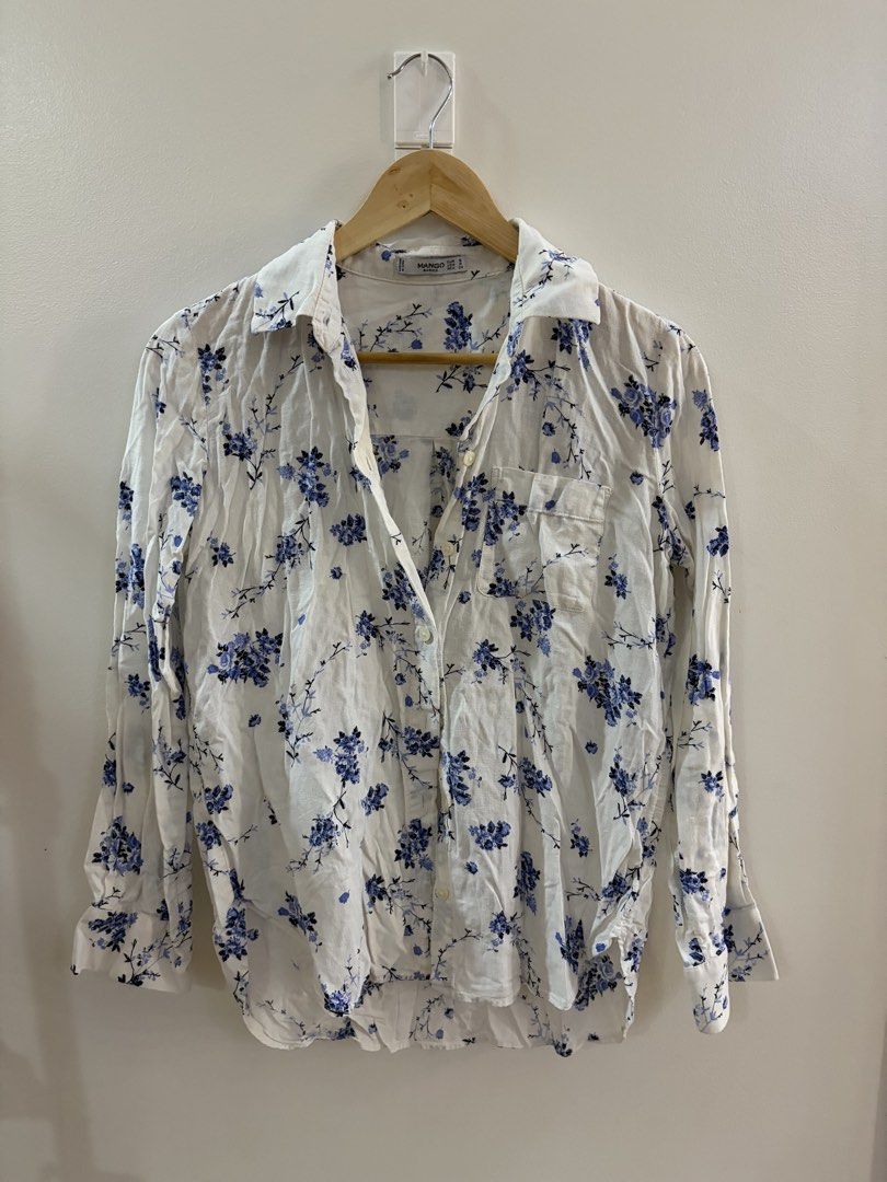Mango Basics White Floral Button-Up Shirt (Category: Longsleeves) located in San Juan City. Submitted by sel.ler (Listing ID 1462126552, Image 1). Description: - Brand: Mango Basics - Color: White with blue floral print - Style: Button-up shirt - Sleeves: Long sleeves with button cuffs - Pockets: Single chest pocket - Material: Lightweight - Occasion: Casual wear.