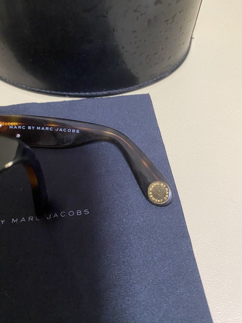 Marc by Marc Jacobs Sunglasses with Case (Category: Sunglasses & Eyewear) located in Agdangan. Submitted by aikara683 (Listing ID 1462054729, Image 2). Description: - Brand: Marc by Marc Jacobs - Style: Sunglasses - Frame Color: Tortoiseshell pattern - Accent Details: Gold accents on arms and front - Included Accessories: Original hard case and cleaning cloth - Perfect for: Sunny days.