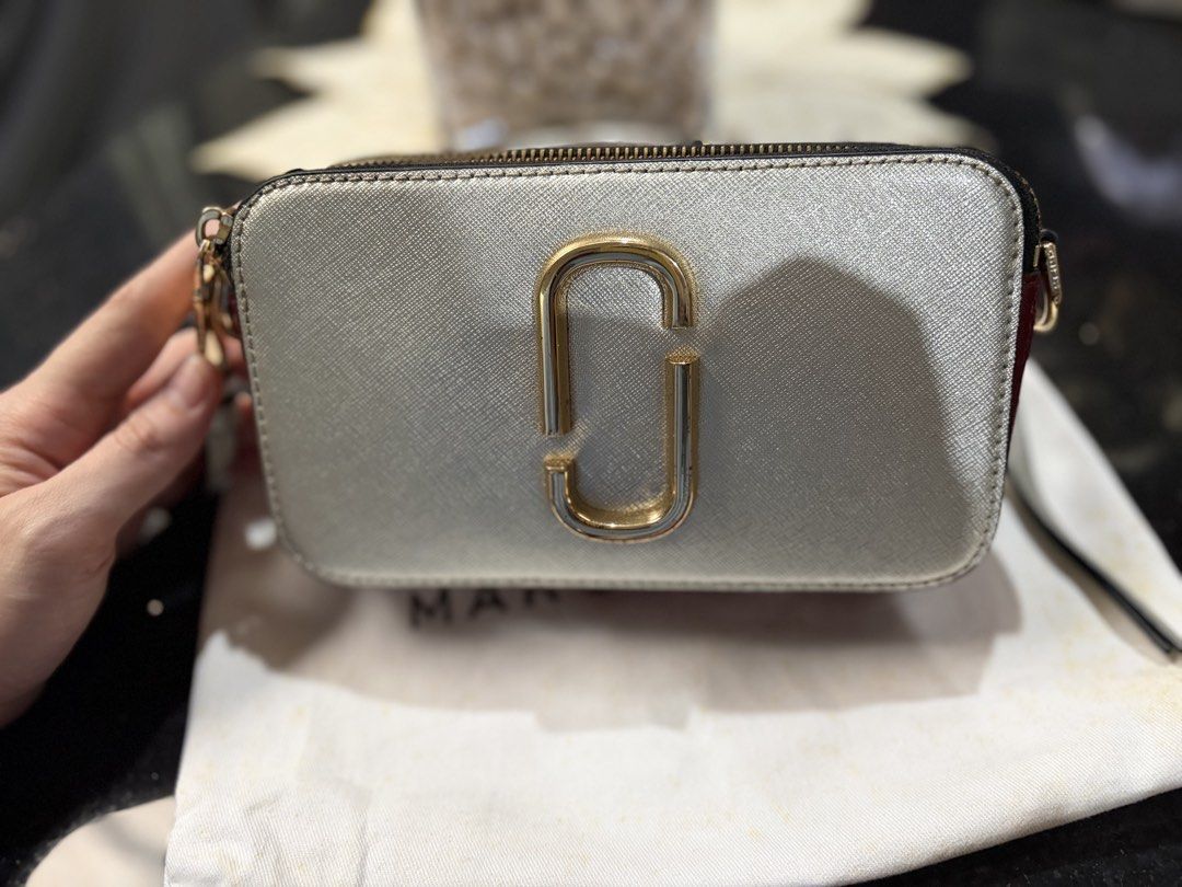 Marc Jacobs Snapshot Camera Bag Silver Burgundy (Category: Luxury Bags & Wallets) located in Cebu City. Submitted by broodie (Listing ID 1462110821, Image 2). Description: - Authentic Marc Jacobs Snapshot camera bag - Chic silver and burgundy Saffiano leather - Features signature gold tone hardware and secure zipper closure - Convenient back pocket for quick access - Comes with the iconic striped strap - Includes original dust bag for protection 