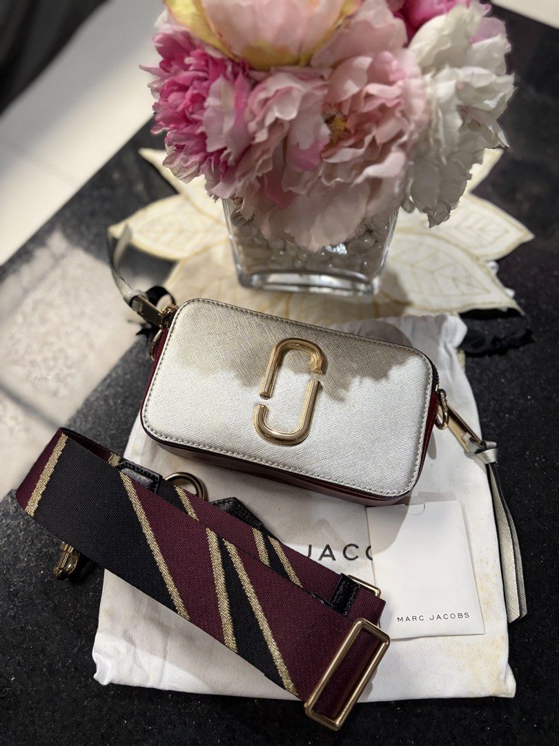 Marc Jacobs Snapshot Camera Bag Silver Burgundy (Category: Luxury Bags & Wallets) located in Cebu City. Submitted by broodie (Listing ID 1462110821, Image 1). Description: - Authentic Marc Jacobs Snapshot camera bag - Chic silver and burgundy Saffiano leather - Features signature gold tone hardware and secure zipper closure - Convenient back pocket for quick access - Comes with the iconic striped strap - Includes original dust bag for protection 