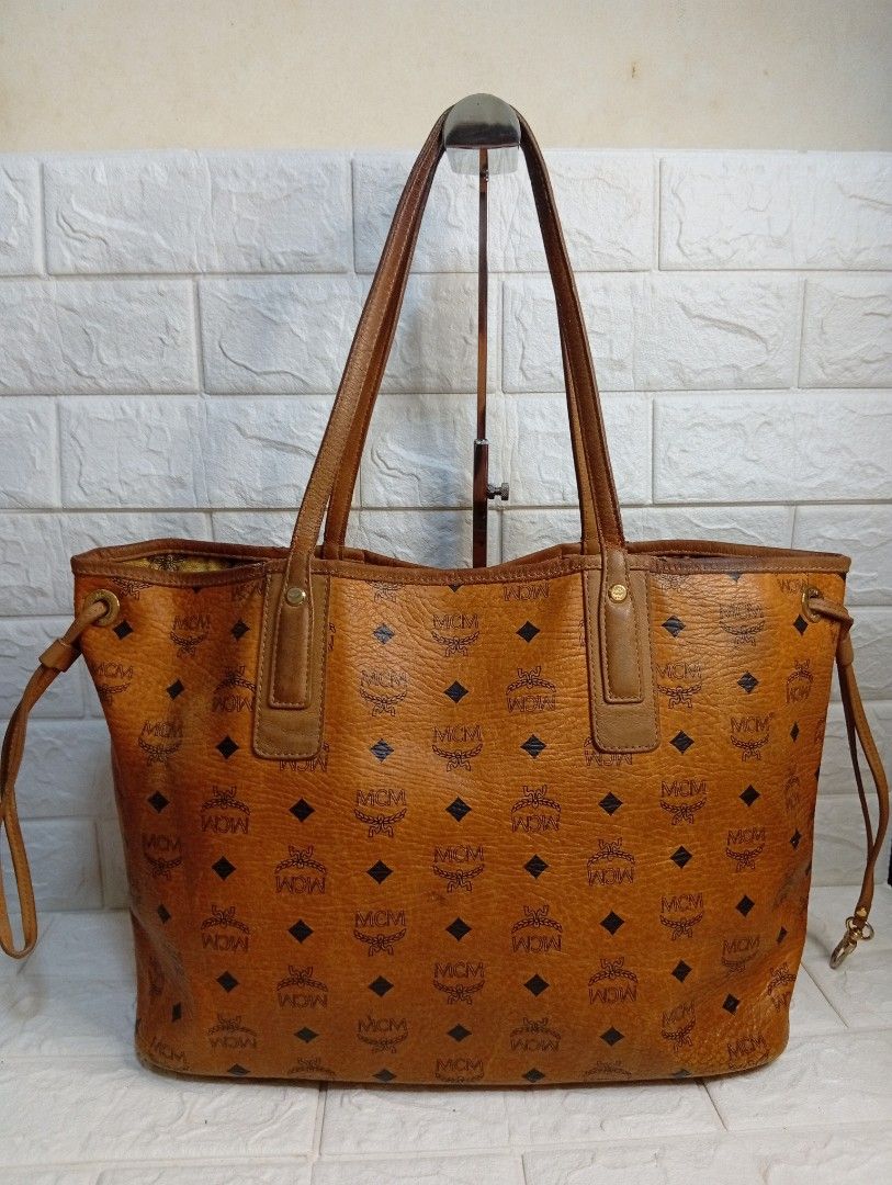 MCM Liz Cognac Reversible Tote Bag (Category: Tote Bags) located in Las Pinas. Submitted by etoksi1234 (Listing ID 1462143156, Image 2). Description: Pre-loved MCM Liz Reversible Shopper tote in cognac brown coated canvas featuring the brand's classic monogram print and dual shoulder straps. (Issue-Crackings on lips)..