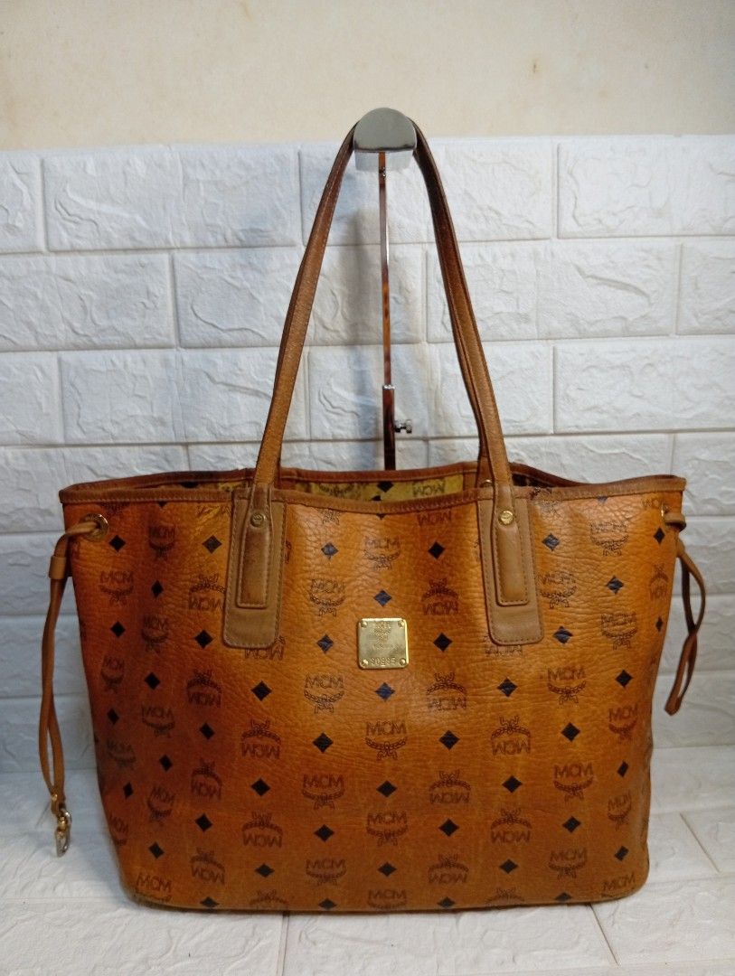 MCM Liz Cognac Reversible Tote Bag (Category: Tote Bags) located in Las Pinas. Submitted by etoksi1234 (Listing ID 1462143156, Image 1). Description: Pre-loved MCM Liz Reversible Shopper tote in cognac brown coated canvas featuring the brand's classic monogram print and dual shoulder straps. (Issue-Crackings on lips)..