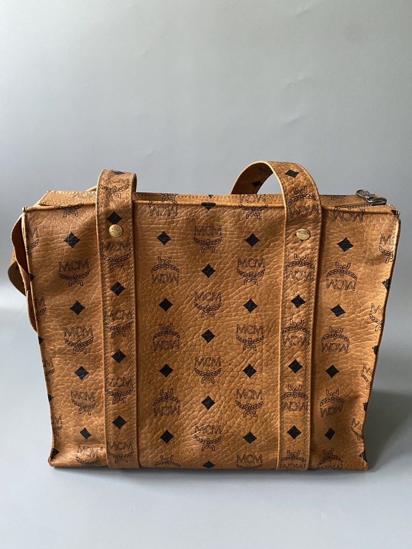 MCM Monogram Tote Bag (Category: Luxury Bags & Wallets) located in Tagbilaran City. Submitted by cay1509 (Listing ID 1462108945, Image 3). Description: - Original Japan bought Classic MCM tote bag - All-over monogram print - Tan leather with black MCM logos - Zipper closure at the top - Interior zippered pocket - Metal logo plate on the front - Comfortable shoulder straps.