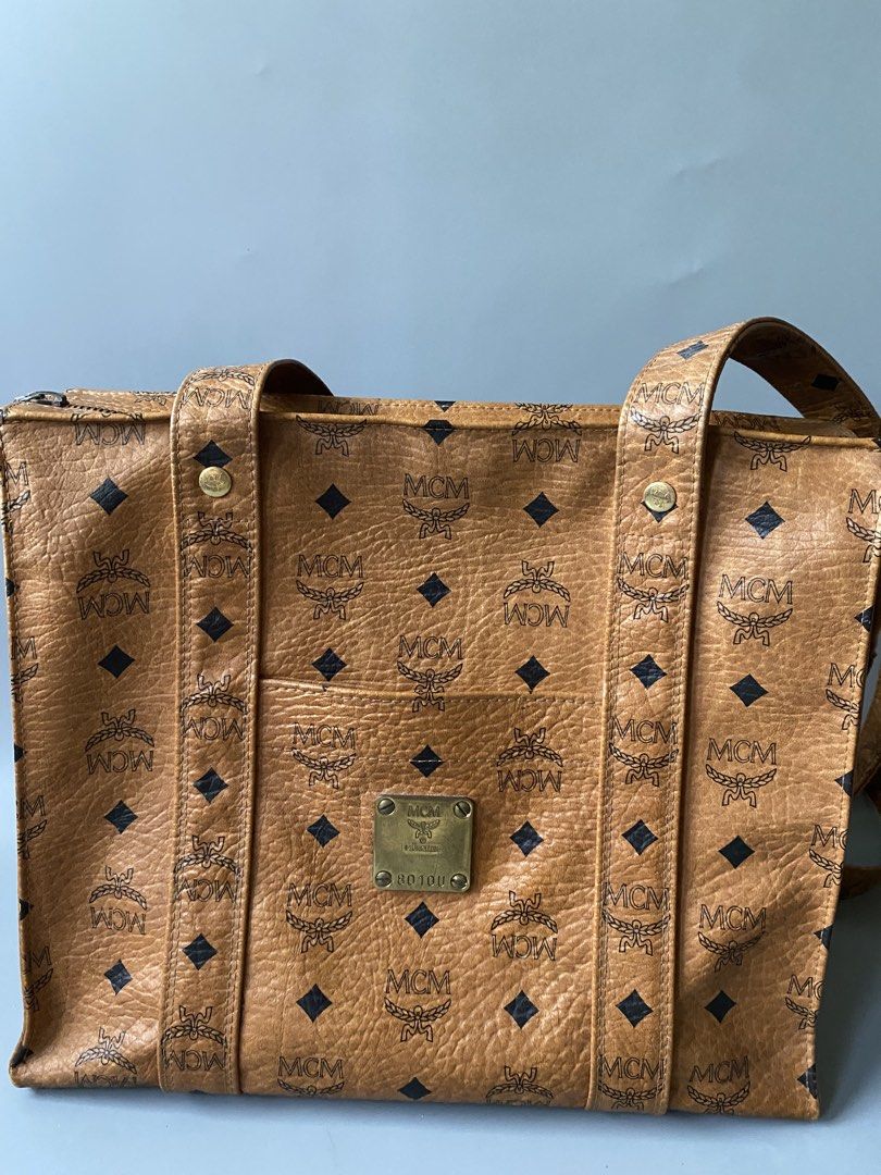 MCM Monogram Tote Bag (Category: Luxury Bags & Wallets) located in Tagbilaran City. Submitted by cay1509 (Listing ID 1462108945, Image 2). Description: - Original Japan bought Classic MCM tote bag - All-over monogram print - Tan leather with black MCM logos - Zipper closure at the top - Interior zippered pocket - Metal logo plate on the front - Comfortable shoulder straps.