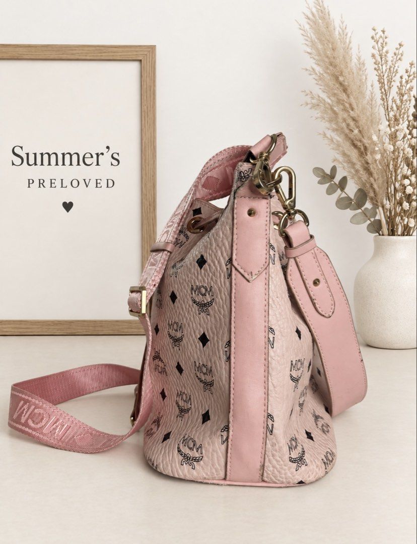 MMC DESSAU DRAWSTRING BAG (Category: Cross-body Bags) located in Taguig. Submitted by summers.preloved (Listing ID 1462227696, Image 2). Description: Bag details: * Pink MMC Visetos monogram exterior * Pebbled coated-canvas finish * Pink leather trim and drawstring closure * Gold-tone eyelets, clasps, buckles, and metal logo plate * Spacious open bucket-style compartment * Interior zip pocket * Wide adjustable MMC webbing strap * Additional pink 