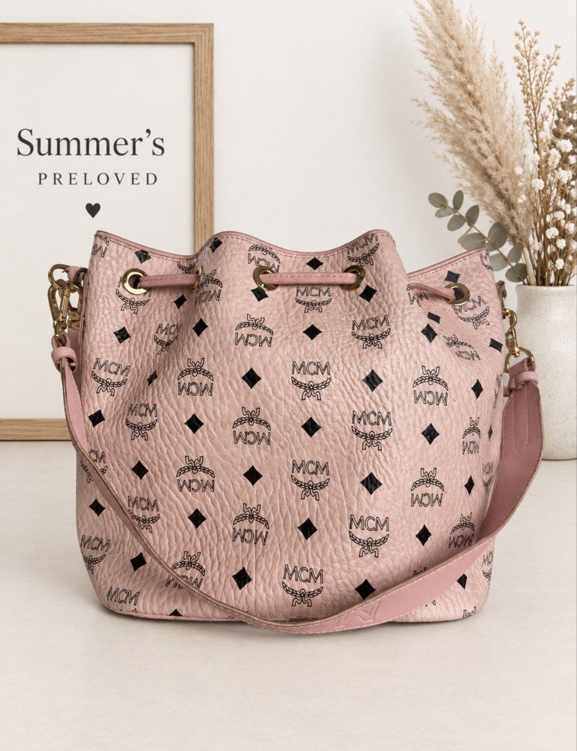 MMC DESSAU DRAWSTRING BAG (Category: Cross-body Bags) located in Taguig. Submitted by summers.preloved (Listing ID 1462227696, Image 3). Description: Bag details: * Pink MMC Visetos monogram exterior * Pebbled coated-canvas finish * Pink leather trim and drawstring closure * Gold-tone eyelets, clasps, buckles, and metal logo plate * Spacious open bucket-style compartment * Interior zip pocket * Wide adjustable MMC webbing strap * Additional pink 