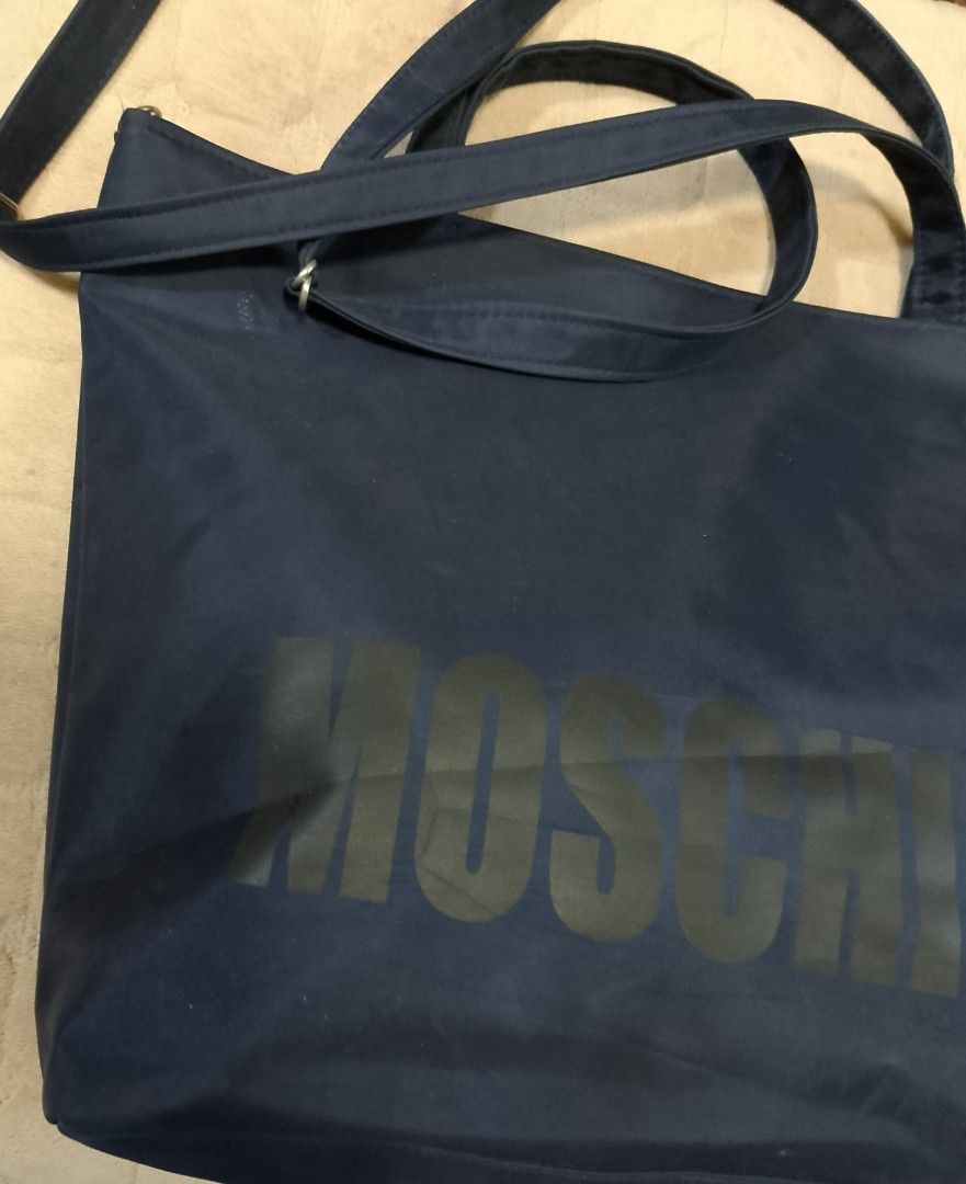 Moschino nylon bag (Category: Shoulder Bags) located in Caloocan City. Submitted by pvaliao (Listing ID 1462079320, Image 3). Description: Moschino nylon bag Brand: Moschino Price: 150 Color: Black Size: 17 inches × 12 inches Material: crafted from a durable , weather resistant nylon shell that offers a slouchy silhouette and easy cleaning. Pre-owned Design: features a classic black color with a subtle printed Moschino branding text graphic cente