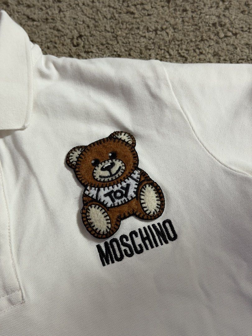 Moschino Teddy Bear Polo Shirt White (Category: Babies & Kids Fashion) located in Quezon City. Submitted by _mgnmn (Listing ID 1462069352, Image 2). Description: - White Moschino polo shirt - Features iconic teddy bear graphic on chest - Bear is wearing a 'TOY' shirt - Simple and classic design - Perfect for casual wear.