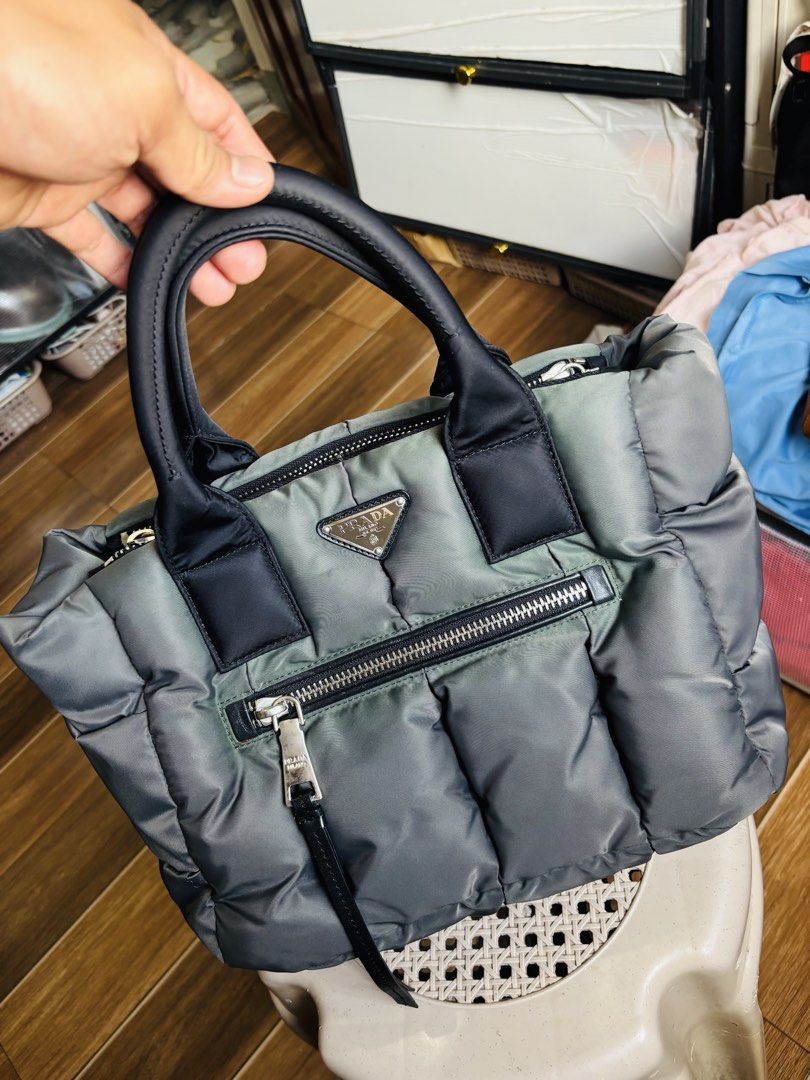 Prada Nylon Puffer Tote Bag Grey (Category: Luxury Bags & Wallets) located in Aroroy. Submitted by paldogs (Listing ID 1462109229, Image 1). Description: - Grey Prada nylon puffer tote - Genuine leather handles and trim - Secure zipper closure - Convenient front zip pocket - Multiple interior compartments for organization -DISCOLORATION - Sleek silver-tone hardware - Ideal everyday bag -NO SLING / STRAP -NO SNAP LOCK.