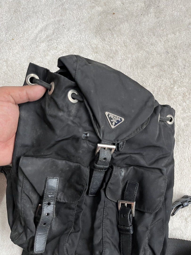 AUTHENTIC Prada Tessuto Nylon BackpackProject Bag (Category: Backpacks) located in General Trias. Submitted by zrchustle.604 (Listing ID 1462178129, Image 2). Description: Prada Tessuto Nylon Backpack, featuring the brand's iconic enameled triangle logo plaque, dual front buckle pockets, and a relaxed drawstring design. Check detailed pics sa issue. Originally debuting in the 1980s, this utilitarian luxury silhouette remains one of Prada's most s