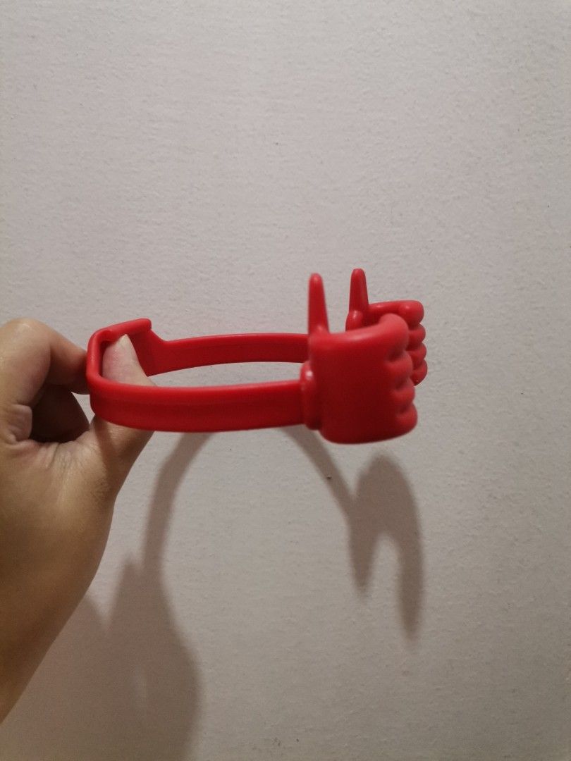 Red "Thumbs Up" Phone Holder Stand (Category: Mounts & Holders) located in Makati City. Submitted by kookybearsstuff (Listing ID 1462114524, Image 2). Description: - Fun red phone holder shaped like a thumbs-up! - Arms securely grip your phone. - Ideal for hands-free viewing on desks or tables. - Perfect for watching videos or making video calls. - Easy to use and portable design..