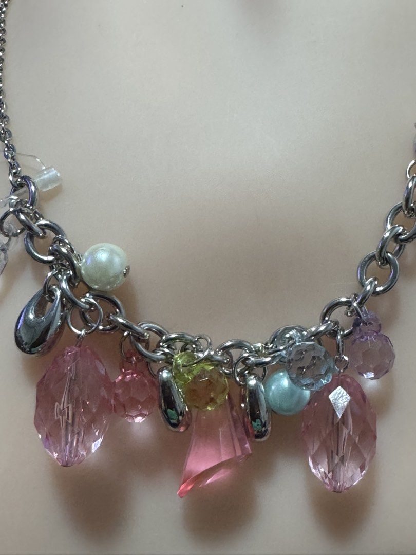 silver-tone charm cluster necklace (Category: Necklaces) located in Angeles City. Submitted by zyeplustradings (Listing ID 1462120257, Image 3). Description: silver-tone charm cluster necklace The design is structured with a simple cable chain that drops into a central bib-style arrangement of multi-shaped drop charms, primarily highlighted by faceted translucent pink teardrop and oval crystals. Interspersed among the pink elements are smaller ac