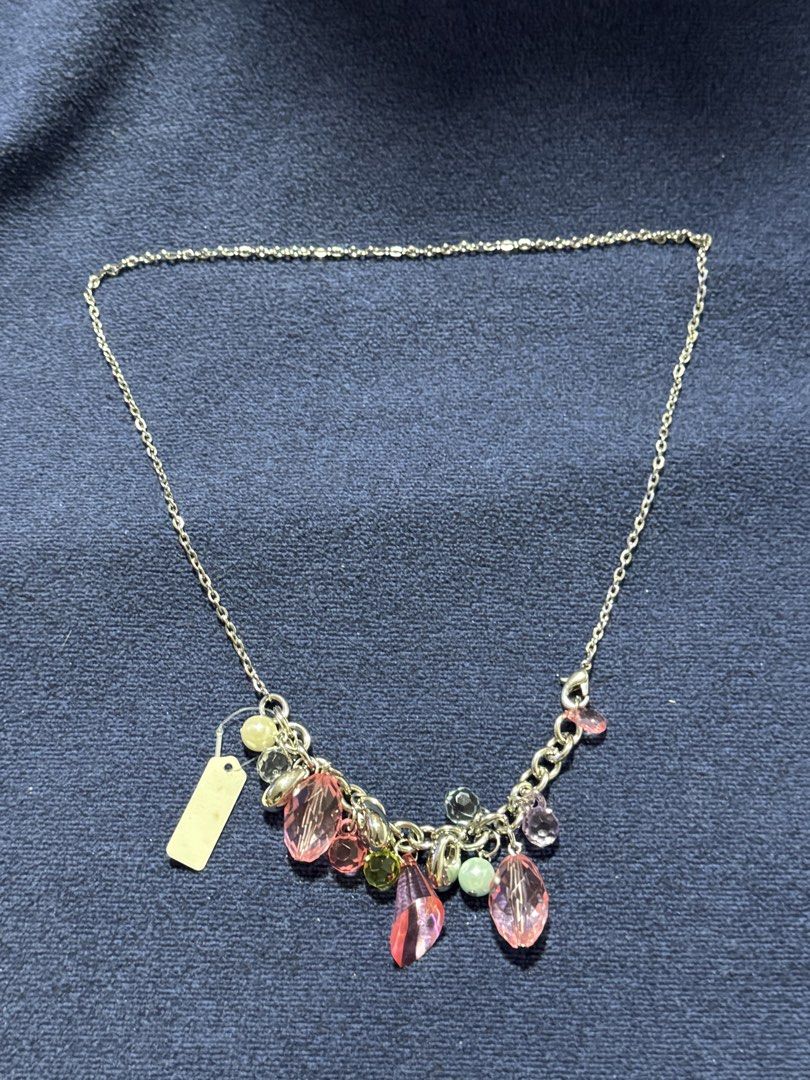 silver-tone charm cluster necklace (Category: Necklaces) located in Angeles City. Submitted by zyeplustradings (Listing ID 1462120257, Image 2). Description: silver-tone charm cluster necklace The design is structured with a simple cable chain that drops into a central bib-style arrangement of multi-shaped drop charms, primarily highlighted by faceted translucent pink teardrop and oval crystals. Interspersed among the pink elements are smaller ac