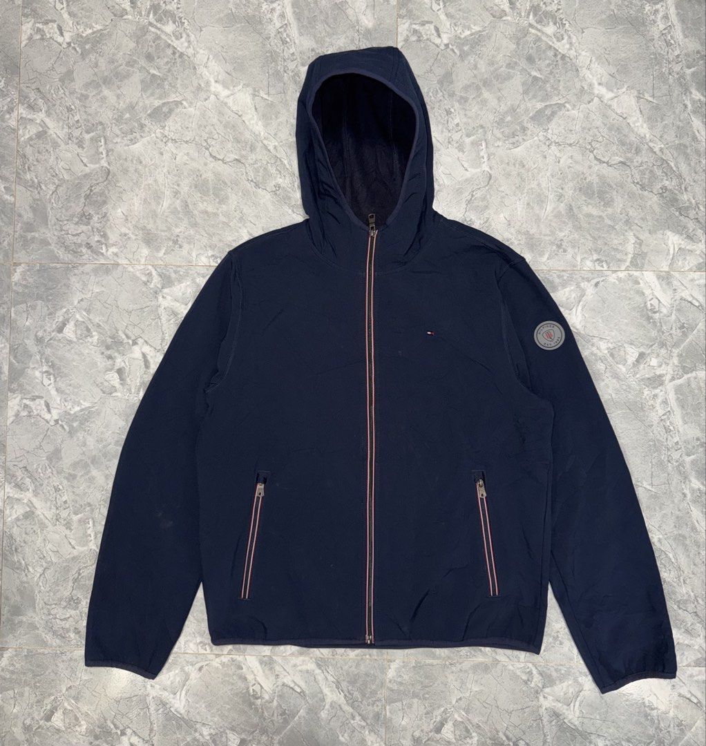 Tommy Hilfiger Navy Blue Hooded Jacket Size M (Category: Coats, Jackets and Outerwear) located in Manila. Submitted by tanlaxfinds (Listing ID 1462047049, Image 1). Description: - Navy blue Tommy Hilfiger hooded jacket - Made of 100% polyester - Fleece-lined interior for warmth - Full zip front closure - Two zippered pockets - Small Tommy Hilfiger logo on chest - Tommy Hilfiger patch on sleeve - Ideal for cooler weather.