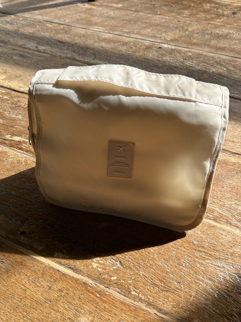 Travel Cosmetic Bag (Category: Luxury Bags & Wallets) located in Surigao. Submitted by chastnavarrete (Listing ID 1462223882, Image 1). Description: - Cream colored travel cosmetic bag - Features a small tag with a plane icon and 'TRAVEL' text - Perfect for organizing toiletries and makeup on the go - Compact and lightweight design - Easy to pack in your luggage.