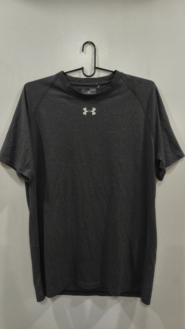 Under armour (Category: Activewear) located in Quezon City. Submitted by secondtonone12 (Listing ID 1462042631, Image 1). Description: Brand: Under Armour. Likely style: Basic performance or training T-shirt, possibly from the UA Tech range. Color: Charcoal gray / dark heather. Construction: Raglan-style sleeves and a rounded crew neck. Logo: White Under Armour logo at the center chest..