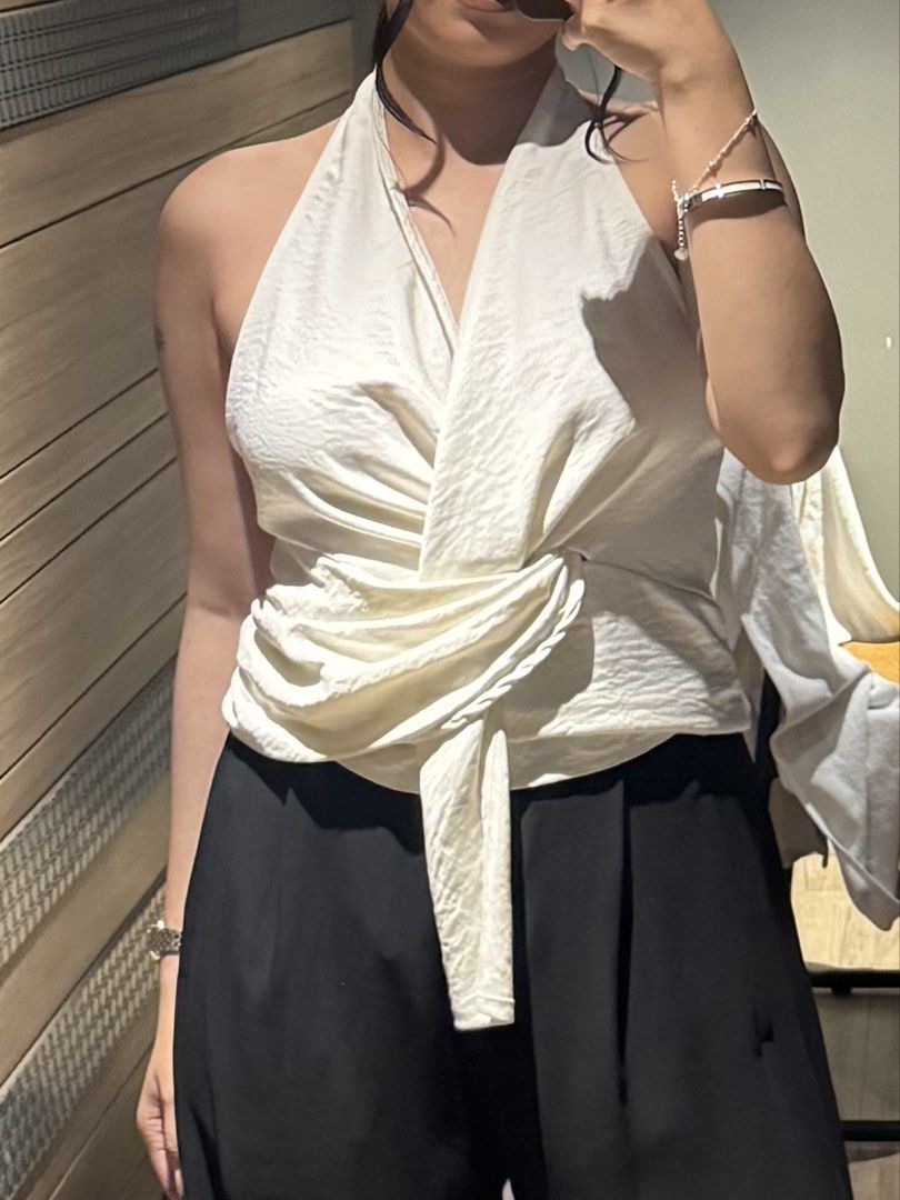 White Twisted Halter Neck Elegant Top (Category: Sleeveless) located in Paranaque City. Submitted by maedizon (Listing ID 1462165579, Image 2). Description: - White halter neck top - Twisted knot detail at the front - Sleeveless design - Silky/satin-like material - Versatile: dress up or down - Pairs well with trousers or skirts - Comfortable and stylish.