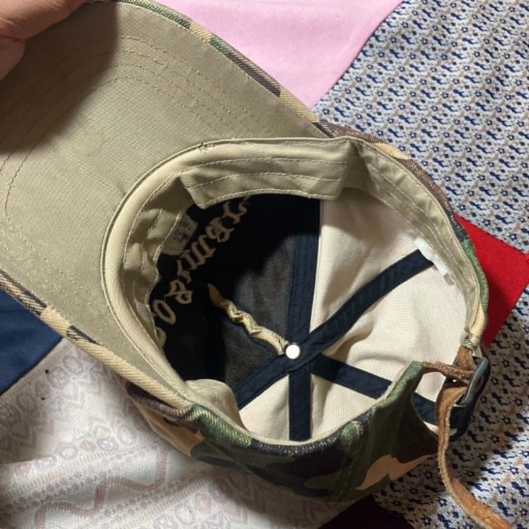 Y2K Grunge Roseman Distressed Camo Baseball Cap (Category: Hats & Beanies) located in Manila. Submitted by nellyfrustrado (Listing ID 1462174675, Image 3). Description: * Brand: Roseman * Style: 6-Panel Distressed Camouflage Baseball Cap. Features raised gothic script "Roseman" embroidery on the crown and a heavily frayed, raw-edge brim. * Material: Heavyweight cotton canvas in a classic woodland camo print, finished with a genuine leather adjust