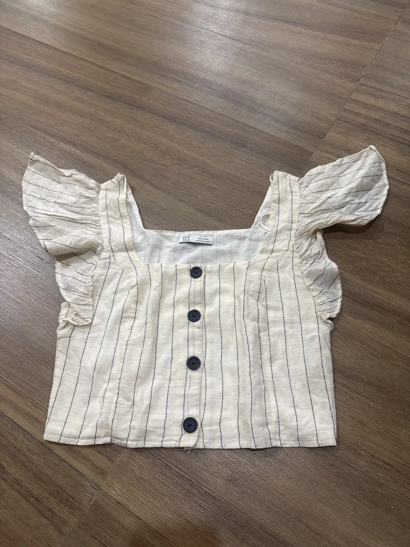 Zara TRF Striped Square Neck Button Up Top (Category: Blouses) located in Makati City. Submitted by curatedclosetco (Listing ID 1462152805, Image 1). Description: - Cream top with thin navy stripes - Square neckline with button-up front - Ruffle cap sleeves - Feels like a linen blend - Versatile for casual or dressed-up looks.