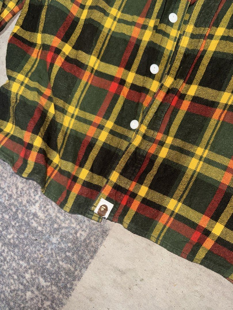 A Bathing Ape BAPE Flannel Shirt (Category: Tshirts & Polo Shirts ) located in Angeles City. Submitted by migs_font29 (Listing ID 1462385056, Image 3). Description: - Classic BAPE flannel shirt - Features iconic ape head logo tag - Green, yellow, and red plaid pattern - Made from 100% cotton - Button-up front with two chest pockets - Versatile for layering or standalone wear.