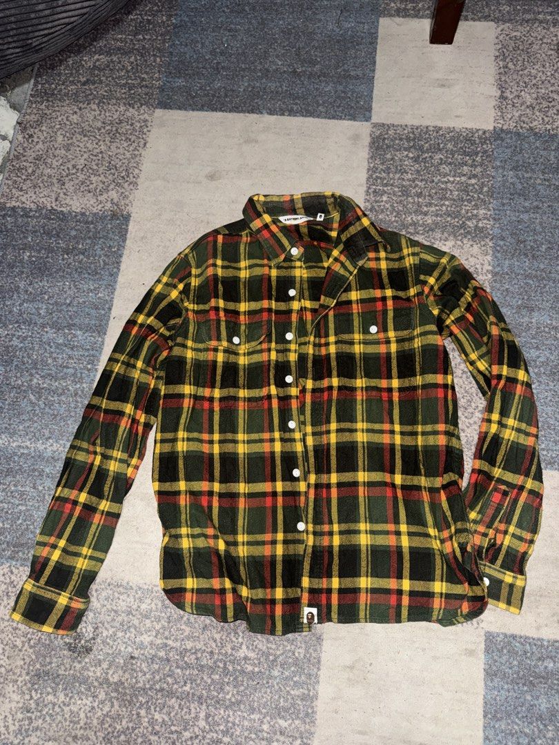 A Bathing Ape BAPE Flannel Shirt (Category: Tshirts & Polo Shirts ) located in Angeles City. Submitted by migs_font29 (Listing ID 1462385056, Image 1). Description: - Classic BAPE flannel shirt - Features iconic ape head logo tag - Green, yellow, and red plaid pattern - Made from 100% cotton - Button-up front with two chest pockets - Versatile for layering or standalone wear.