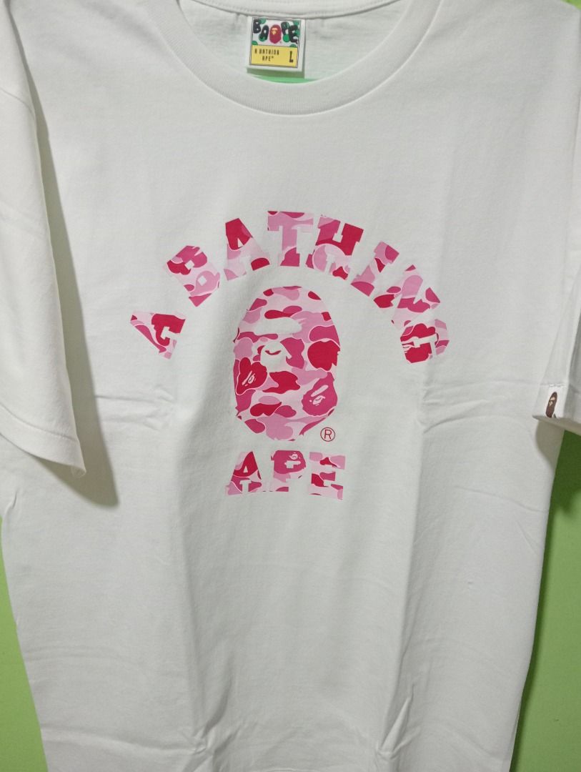 A Bathing Ape BAPE Pink Camo Ape Head Tee (Category: Tshirts & Polo Shirts ) located in Caloocan City. Submitted by yazzielux (Listing ID 1462431893, Image 2). Description: - Authentic White A Bathing Ape T-Shirt - Features iconic pink camo Ape Head graphic - Arch logo across the chest - Comes in original packaging - Size: Large (L) - Essential piece for any streetwear collection.