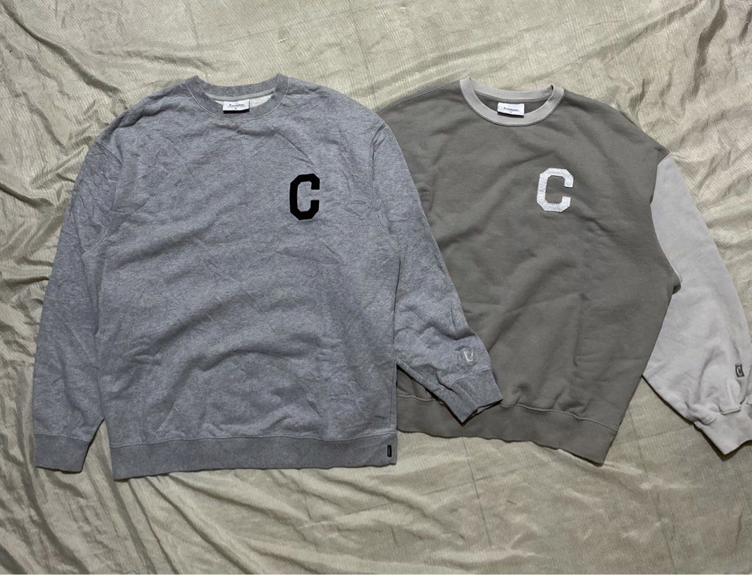 ASPACK ‼️ Covernat pullover (Category: Coats, Jackets and Outerwear) located in Davao. Submitted by chazethrift (Listing ID 1462351041, Image 1). Description: - Two Champion sweatshirts available. - Sweatshirt 1: Solid grey with black 'C' logo. - Sweatshirt 2: Brown and light grey colorblock with white 'C' logo. - Both feature the iconic Champion logo detail on the sleeve cuff. - Ideal for comfortable and stylish casual wear..