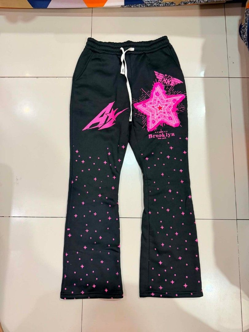 Black Brooklyn Star Flare Sweatpants (Category: Other Bottoms) located in Manila. Submitted by thrift.glaizee (Listing ID 1462429205, Image 1). Description: - Black sweatpants with pink star graphic and 'Brooklyn' text on left leg - Scattered pink star and dot pattern down the legs - Flare leg opening - Drawstring waist - Ideal for casual wear.