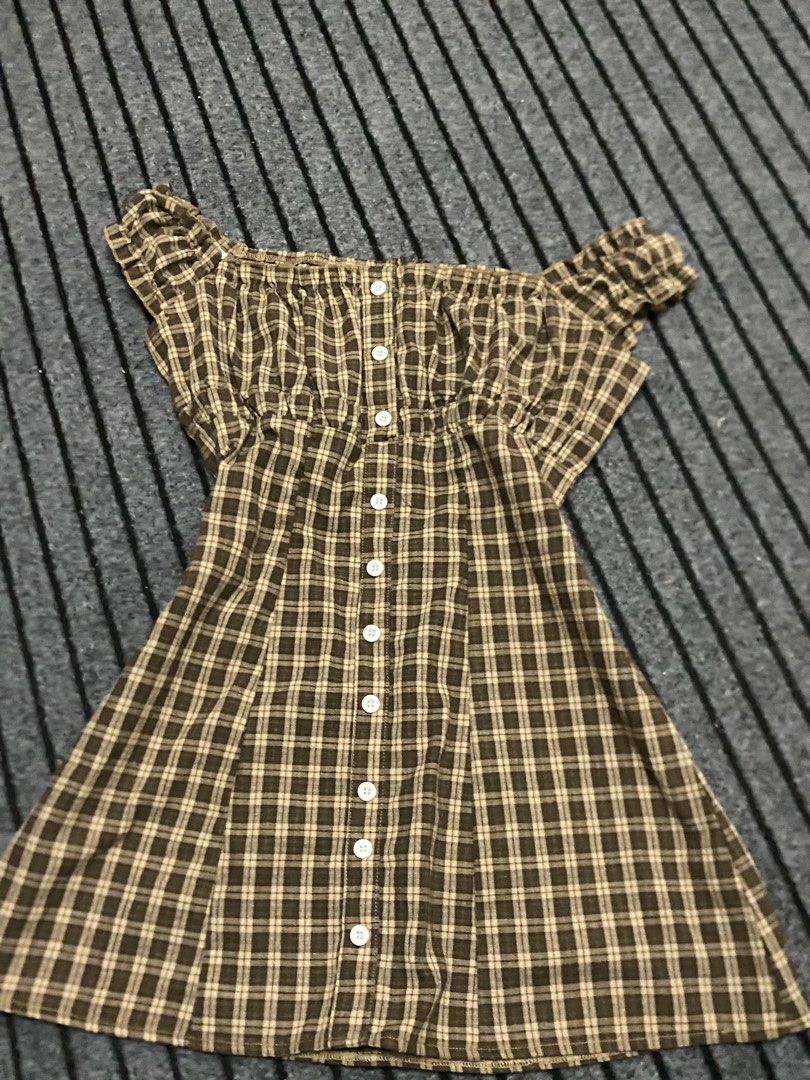 Brown Plaid Off-Shoulder Button-Up Dress (Category: Dresses) located in Manila. Submitted by ysabellade60459 (Listing ID 1462366254, Image 2). Description: - Adorable brown plaid dress - Chic off-shoulder design with shirred bodice - Functional buttons down the front - Flattering short flutter sleeves - Slightly flared hem for a playful look - Ideal for casual wear, picnics, and sunny days.