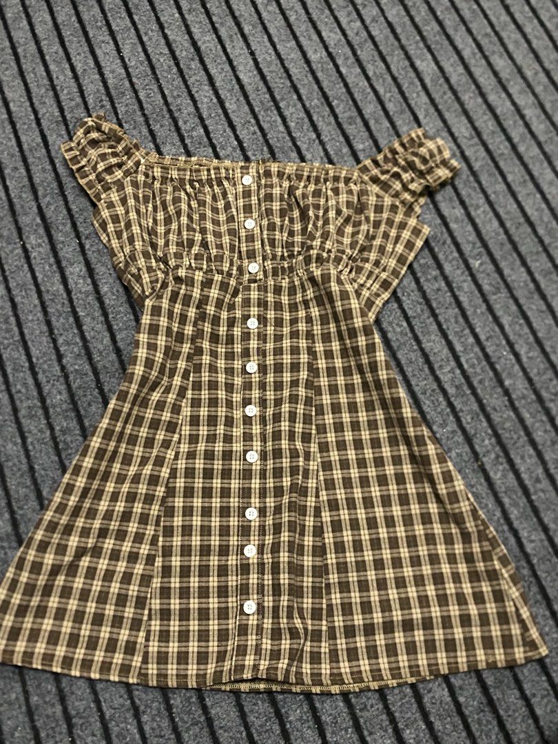 Brown Plaid Off-Shoulder Button-Up Dress (Category: Dresses) located in Manila. Submitted by ysabellade60459 (Listing ID 1462366254, Image 1). Description: - Adorable brown plaid dress - Chic off-shoulder design with shirred bodice - Functional buttons down the front - Flattering short flutter sleeves - Slightly flared hem for a playful look - Ideal for casual wear, picnics, and sunny days.