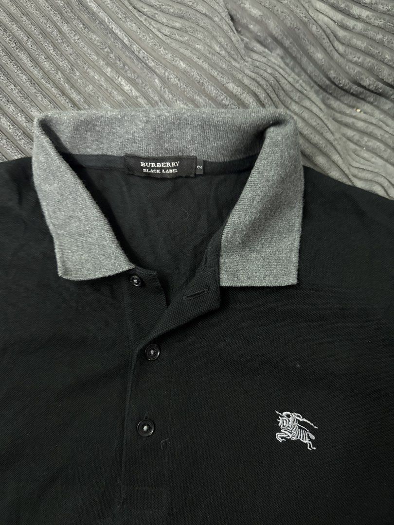 Burberry Black Label Polo Shirt (Category: Tshirts & Polo Shirts ) located in Angeles City. Submitted by migs_font29 (Listing ID 1462391783, Image 2). Description: - Authentic Burberry Black Label polo shirt - Size: 2 - Color: Black with grey collar and sleeve details - Features iconic Burberry knight logo on the chest - Large 'B' logo detail on the sleeve - Perfect for stylish casual wear.