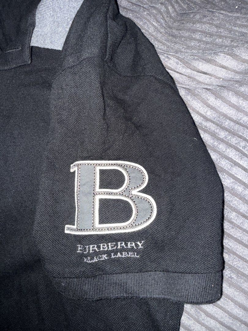 Burberry Black Label Polo Shirt (Category: Tshirts & Polo Shirts ) located in Angeles City. Submitted by migs_font29 (Listing ID 1462391783, Image 3). Description: - Authentic Burberry Black Label polo shirt - Size: 2 - Color: Black with grey collar and sleeve details - Features iconic Burberry knight logo on the chest - Large 'B' logo detail on the sleeve - Perfect for stylish casual wear.