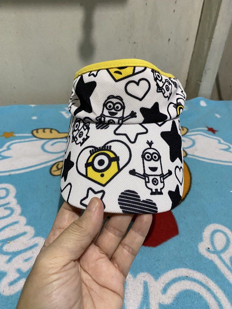 Castelbajac Minions Visor Cap (Category: Caps & Hats) located in Manila. Submitted by resi.diaz (Listing ID 1462400044, Image 2). Description: - Adorable visor cap featuring a fun Minions print. - Playful black stars and hearts scattered across the design. - Bright yellow trim and brim for a pop of color. - Adjustable strap at the back for a comfortable, customized fit. - Ideal accessory for sunny days and outdoor adventures. - A must-have for an