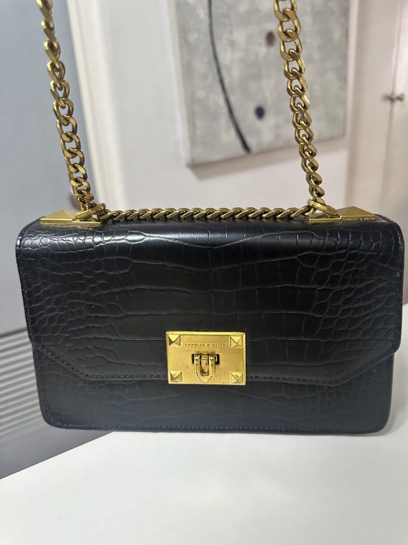 Charles & Keith Black Croc Embossed Chain Shoulder Bag (Category: Shoulder Bags) located in Quezon City. Submitted by fashion4less__ (Listing ID 1462347965, Image 1). Description: - Black shoulder bag with stylish croc-embossed texture. - Elegant gold chain strap and hardware. - Secure turn-lock closure. - Includes an interior zippered compartment for essentials. - Ideal for evening events or adding a touch of sophistication to your look..