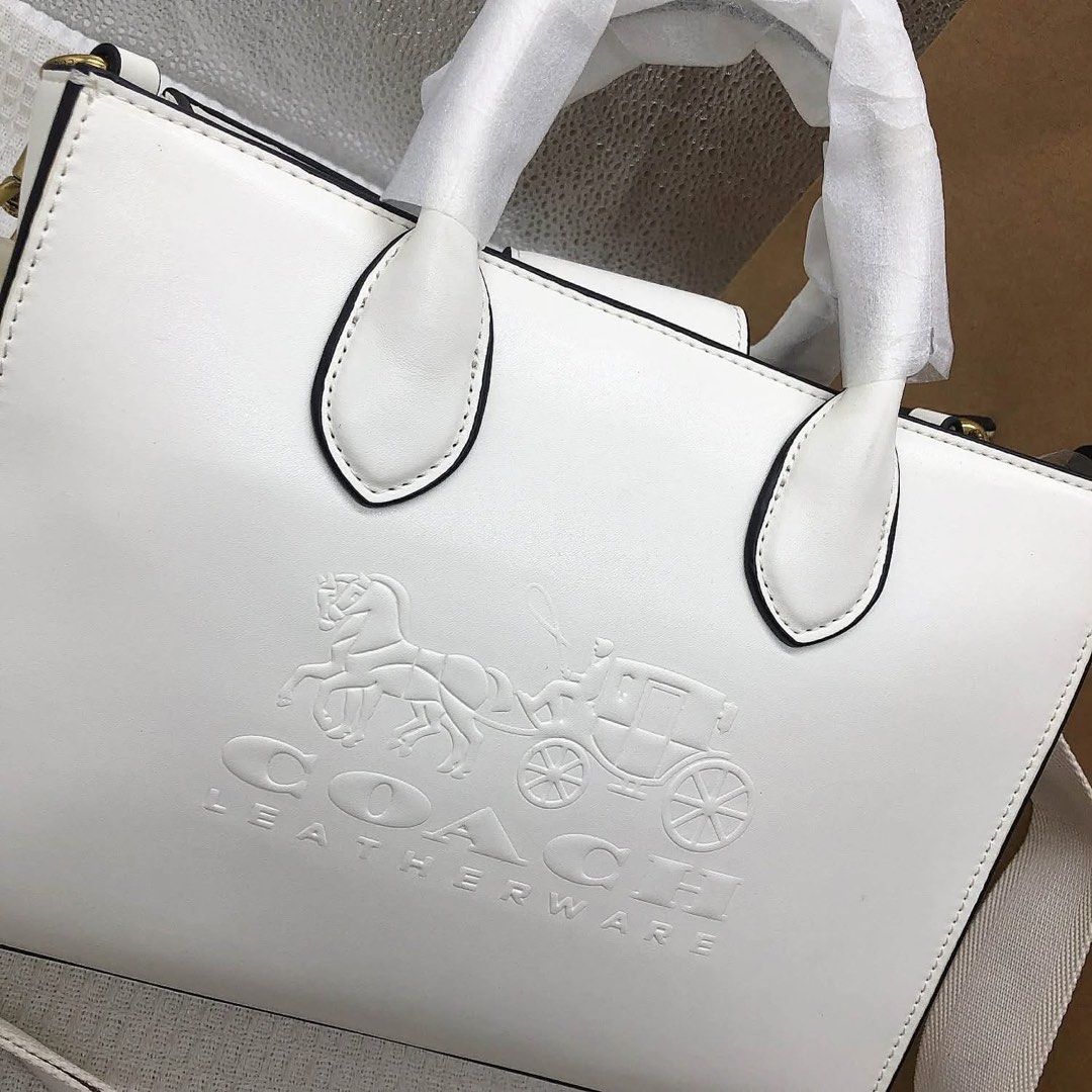 Coach Leatherware White Tote Bag with Strap (Category: Community) located in Angeles City. Submitted by migs_font29 (Listing ID 1462433470, Image 3). Description: - Authentic Coach tote bag - Embossed horse and carriage logo on front - Elegant leatherware details - Detachable shoulder strap included - Luxurious brown suede interior lining - Secure zipper closure - Comes with original silica gel packet.