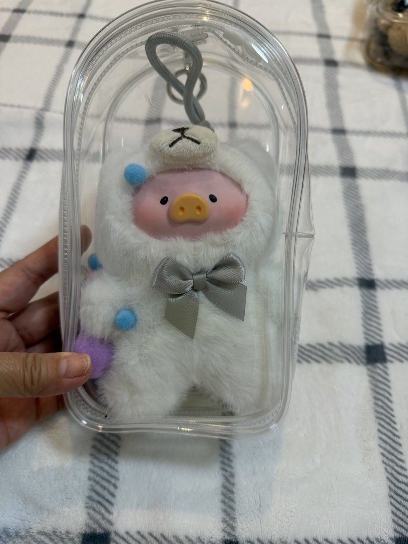 Cute Pig Plush Keychain in Clear Case (Category: Plushies & Soft Toys) located in Cavite. Submitted by truecat_2ac10c (Listing ID 1462300937, Image 1). Description: - Adorable fluffy pig plushie - Features a cute bear hat - Wears a little grey bow - Comes in a clear protective case - Includes a keychain loop - Decorated with colorful pom-poms - Ideal for decorating bags or backpacks - Fun and charming accessory.