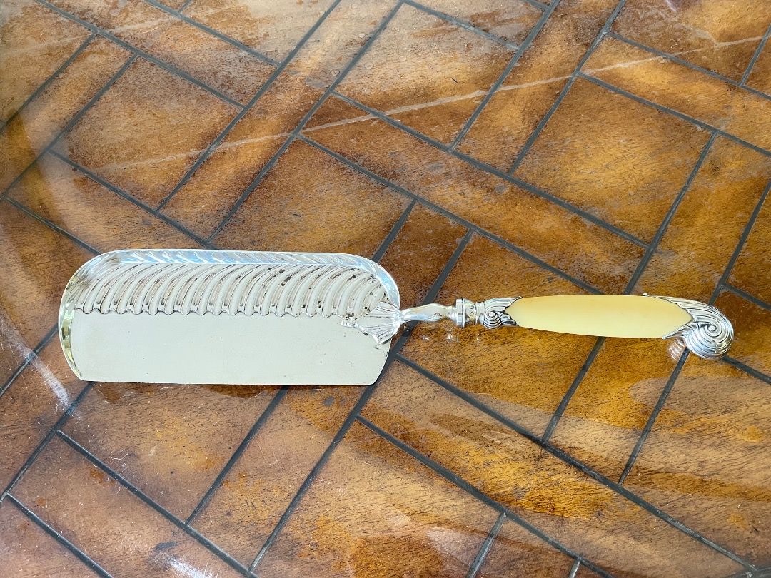 Edwardian Solid Silver and Ivory Crumb Scoop (Category: Vintage Collectibles) located in Caloocan City. Submitted by eu_antiques53 (Listing ID 1462390447, Image 1). Description: 1901-1910 - Hallmarked for London 1905/6 with makers mark for William Hutton & Sons. - With an ivory handle embellished with hallmarked silver scrolling and fluted mounts Length: 35cm Width : 7cm (at widest point) Weight: 266 grams.