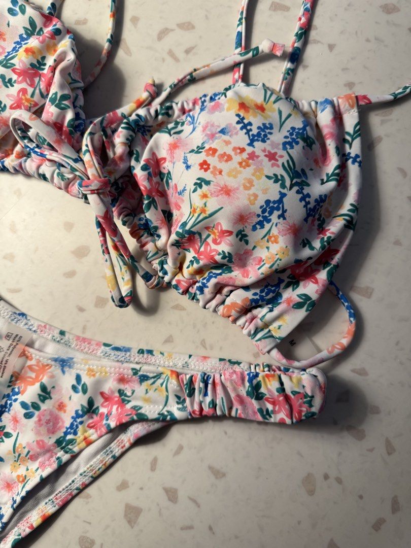 Floral Print Bikini Set (Category: Bikinis & Swimsuits) located in Las Pinas. Submitted by patringcia_14 (Listing ID 1462319239, Image 3). Description: - Adorable floral print bikini - White base with vibrant pink, yellow, blue, and green flowers - Halter neck top with adjustable tie details - Matching cheeky bottoms with elasticated waistband - Comfortable elasticated straps - Ideal for beach days and poolside lounging.