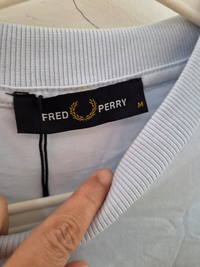 Fred Perry Light Blue T-Shirt Size M (Category: Tshirts & Polo Shirts ) located in Taytay. Submitted by passiveincome89 (Listing ID 1462269778, Image 3). Description: - Light blue Fred Perry T-shirt - Black square graphic with laurel wreath design on front - Size: Medium (M) - Ideal for casual wear - Authenticity Unknown.