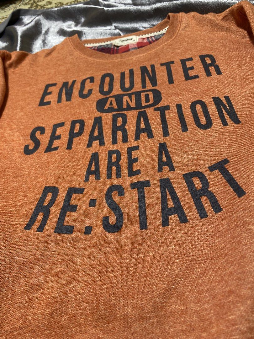 Gembony Orange Graphic Sweatshirt M (Category: Longsleeves) located in Agdangan. Submitted by kevinthriftshop (Listing ID 1462301373, Image 3). Description: - Brand: Gembony - Color: Orange - Size: M - Graphic print on front: 'ENCOUNTER AND SEPARATION ARE A RE:START' - Plaid lining around the collar - Material: Polyester and Cotton blend.