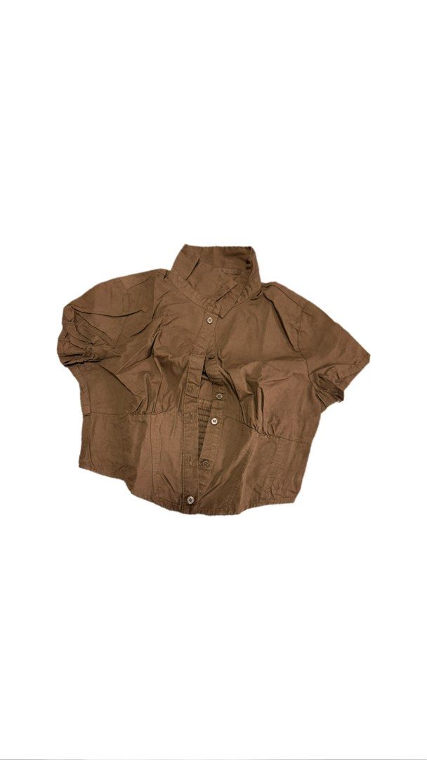 H&M Brown Cropped Button-Up Shirt (Category: Shirts) located in Paranaque City. Submitted by nikadeclutters (Listing ID 1462341938, Image 1). Description: - Chic brown cropped shirt - Button-up front with collared neckline - Short, stylish puff sleeves - Elasticated waist for a flattering, cinched look - Versatile for casual or dressed-up outfits.