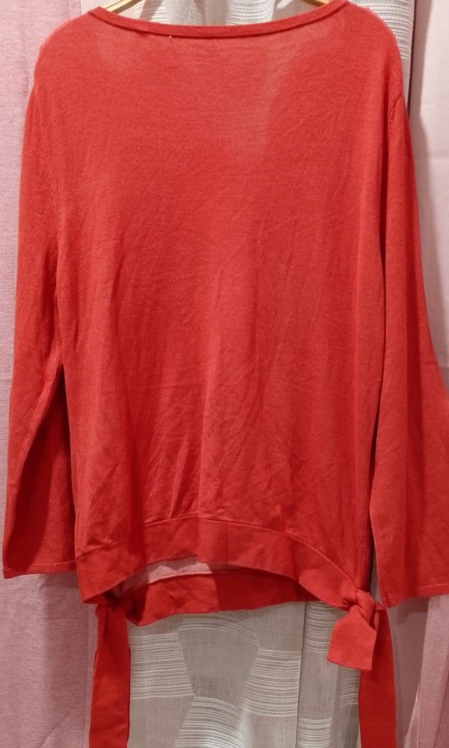 Knitted coral orange tops (Category: Blouses) located in Cabanatuan. Submitted by miss.maia (Listing ID 1462433982, Image 2). Description: The image shows a coral-red long-sleeve knit top with a wide scoop neckline and side-tie knot details at the hem..