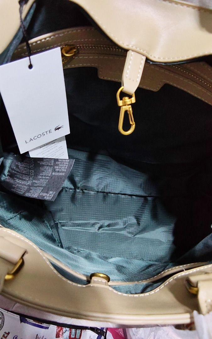 Lacoste Beige Monogram Tote Bag (Category: Tote Bags) located in Caloocan City. Submitted by jpmshoppe (Listing ID 1462317050, Image 2). Description: - Stylish beige tote bag - Features a geometric monogram pattern - Elegant gold hardware details - Interior lined with dark green fabric - Secure clasp closure inside - Spacious enough for all your essentials - Comes with original tags attached - Perfect for everyday use or special occasions.
